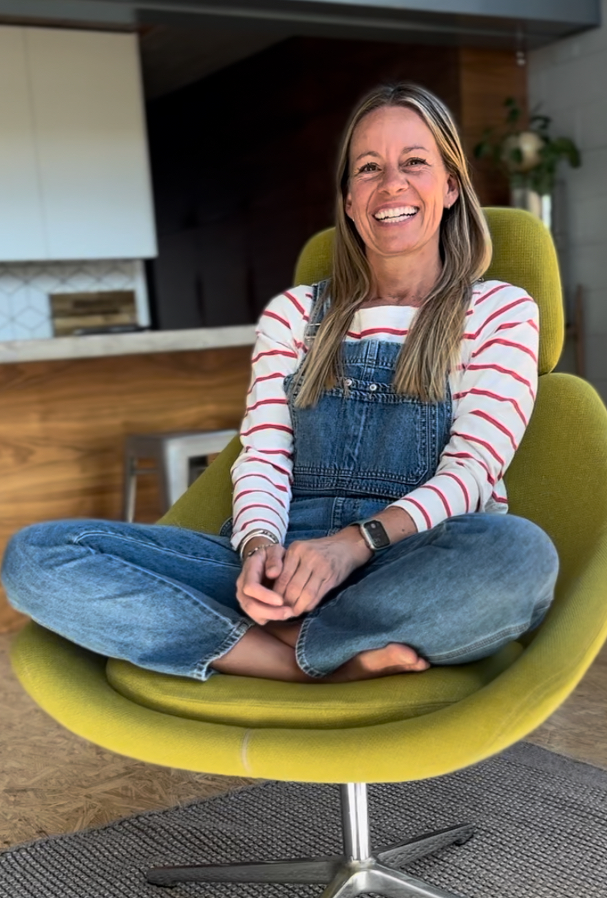 A woman sitting on a mid century modern chair in a clean, organized living room